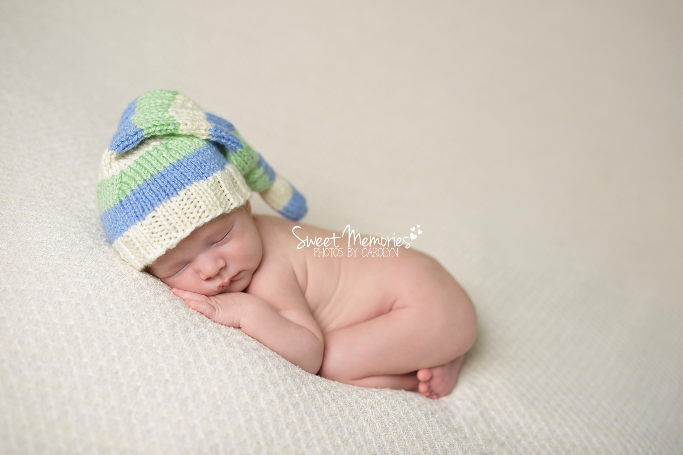 newborn boy with blue green and white hat