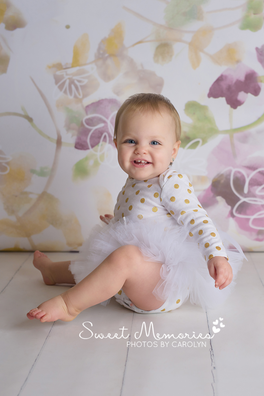 Purple and gold floral backdrop with smiling one year old girl in a tutu. First birthday pictures in Quakertown, PA | Sweet Memories Photos by Carolyn