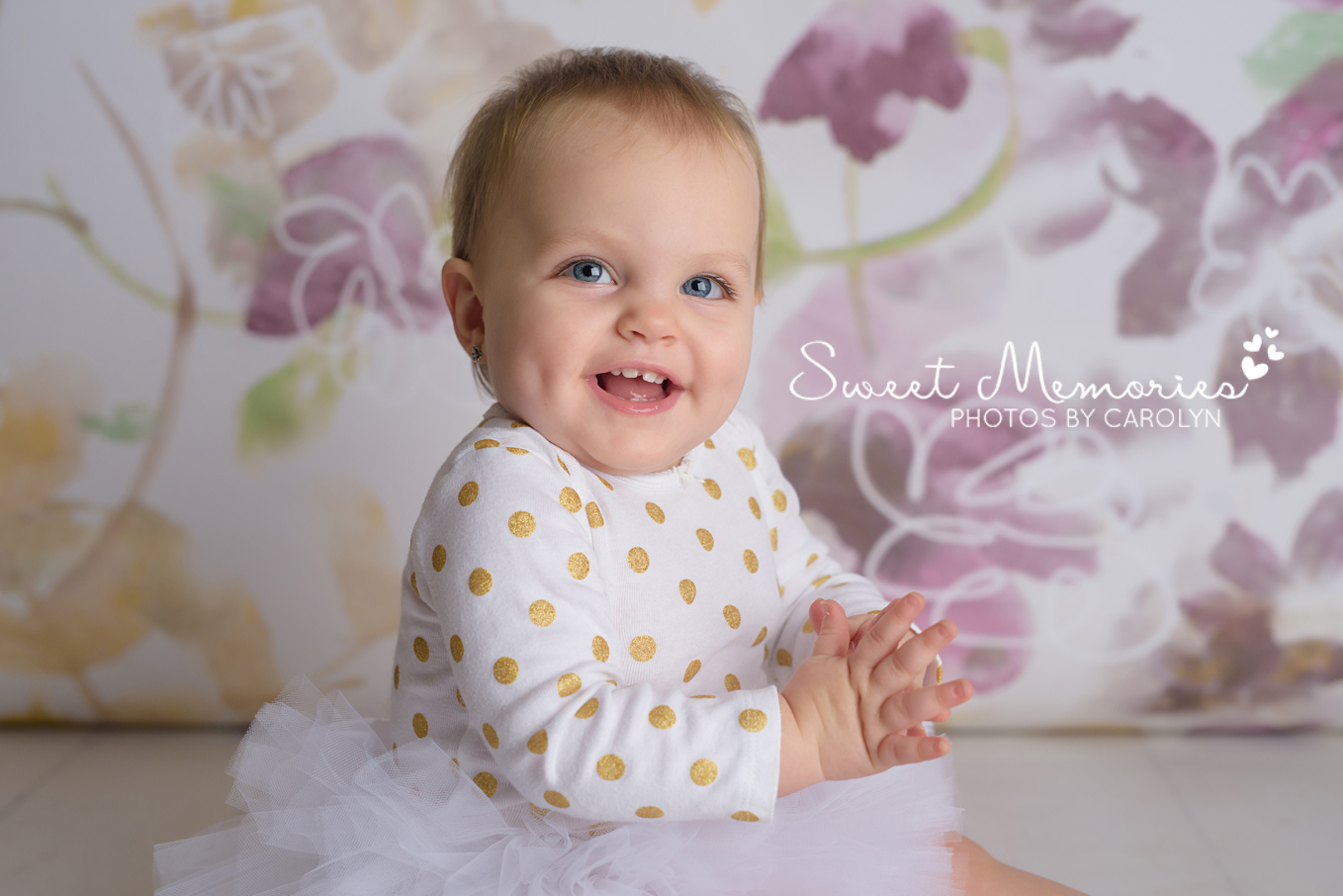 Purple and gold floral backdrop with close up of smiling and clapping one year old girl in a tutu Quakertown, PA | Sweet Memories Photos by Carolyn
