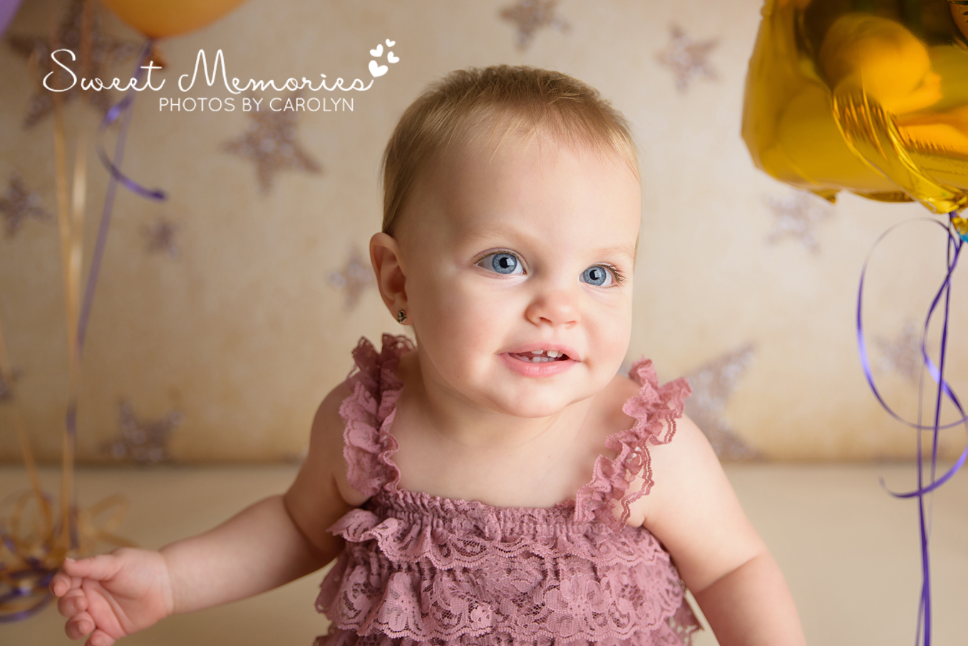close up of smiling one year old girl on gold star backdrop with purple lace romper in Quakertown | Sweet Memories Photos by Carolyn 