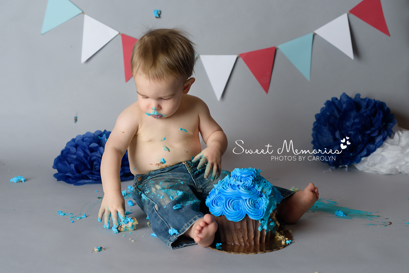 messy one year old boy cake smash on gray background with large blue cupcake  | Sweet Memories Photos by Carolyn