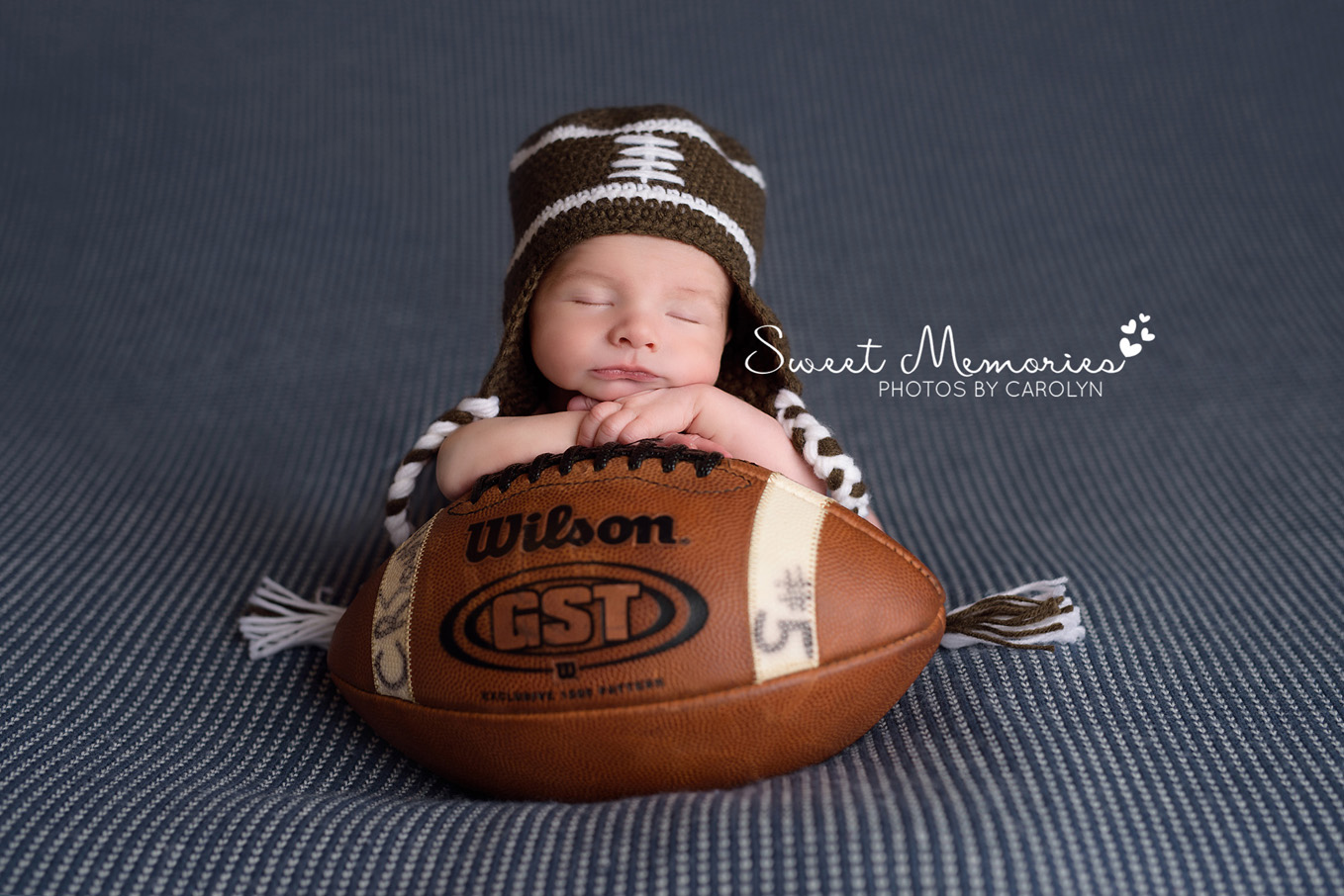 newborn boy in football hat resting on dad's football in Newtown | Sweet Memories Photos by Carolyn