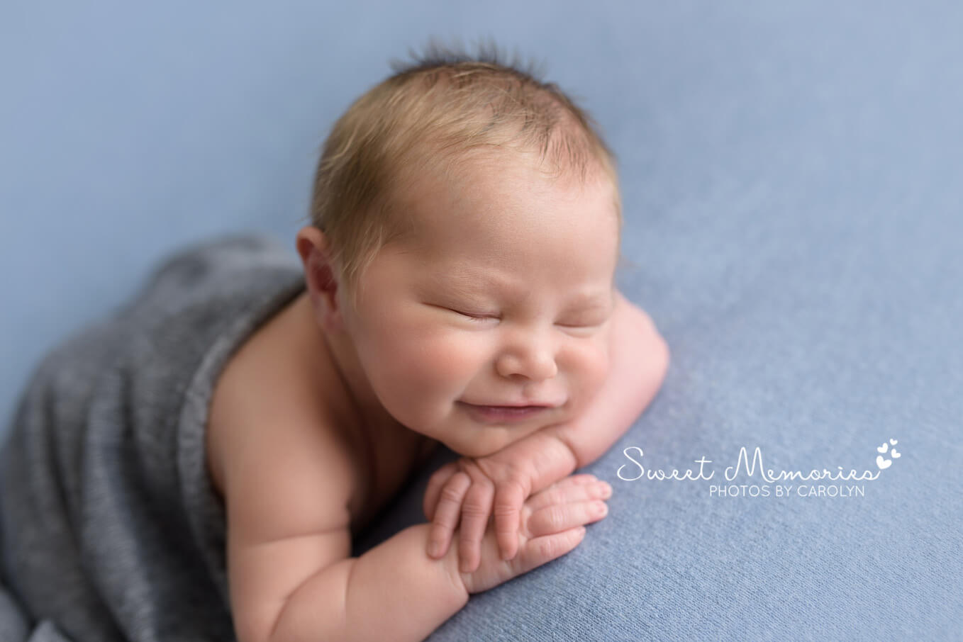 baby boy sleeping and smiling on blue blanket