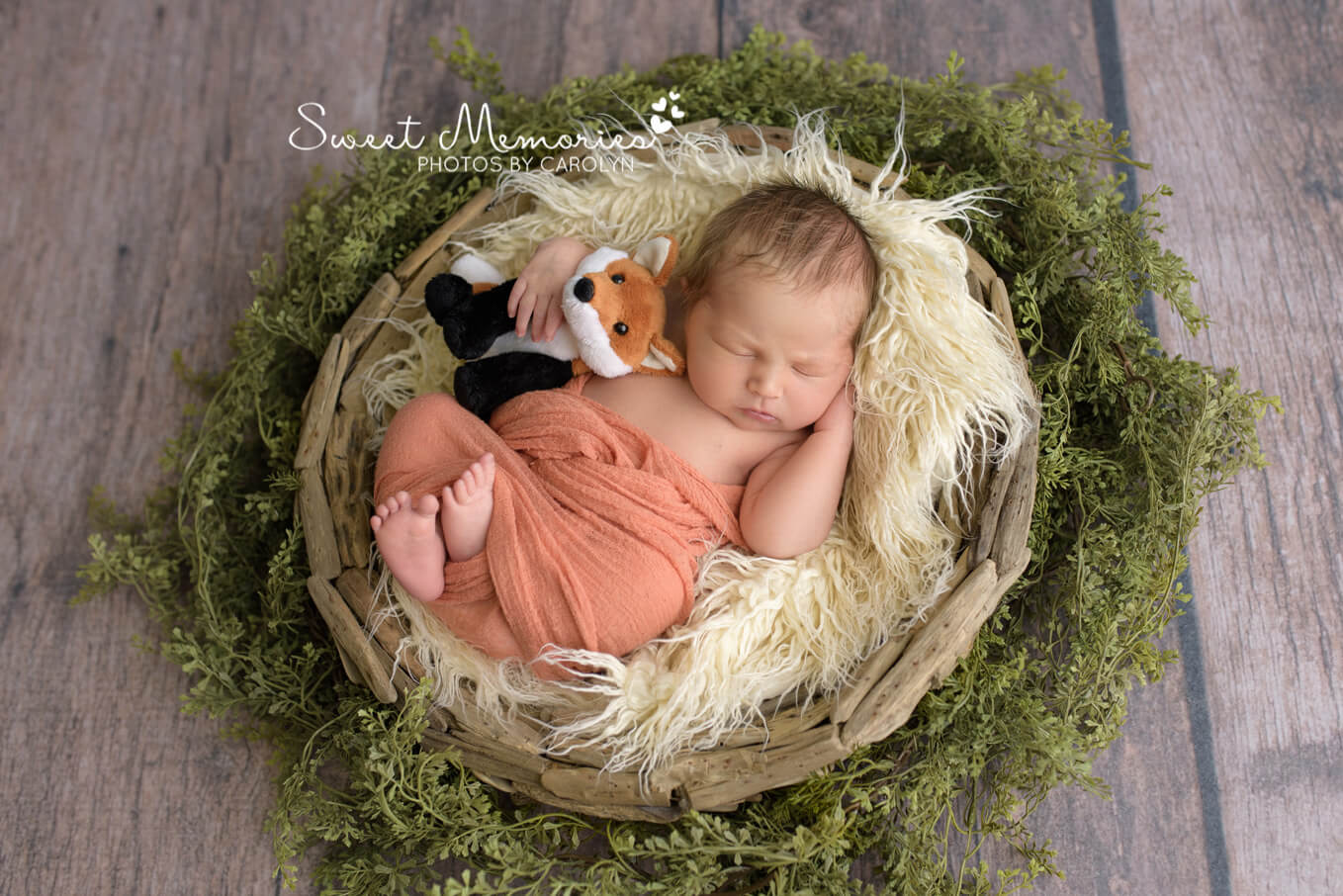newborn boy swaddled in orange holding stuffed fox