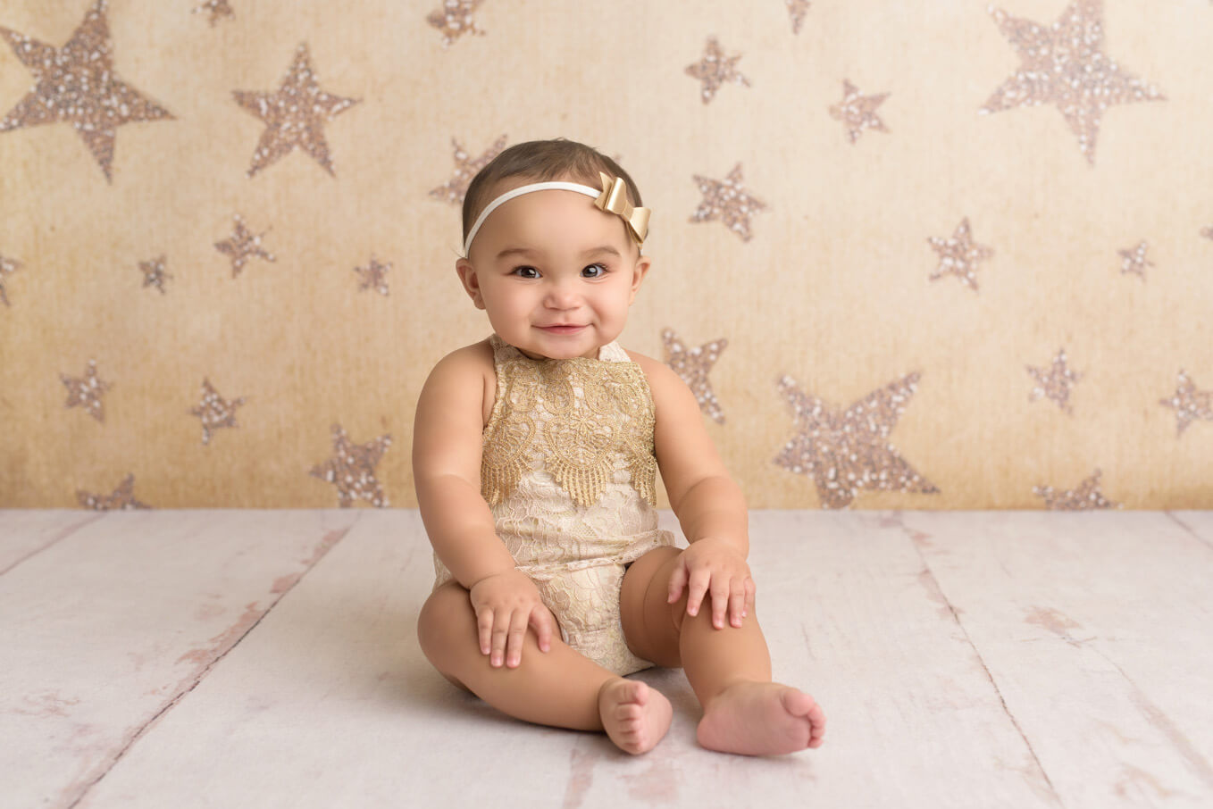 one year old baby sitting with star backdrop