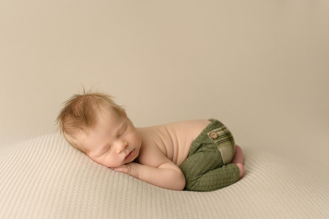 Austin newborn photographer boy in green pants on tan backdrop