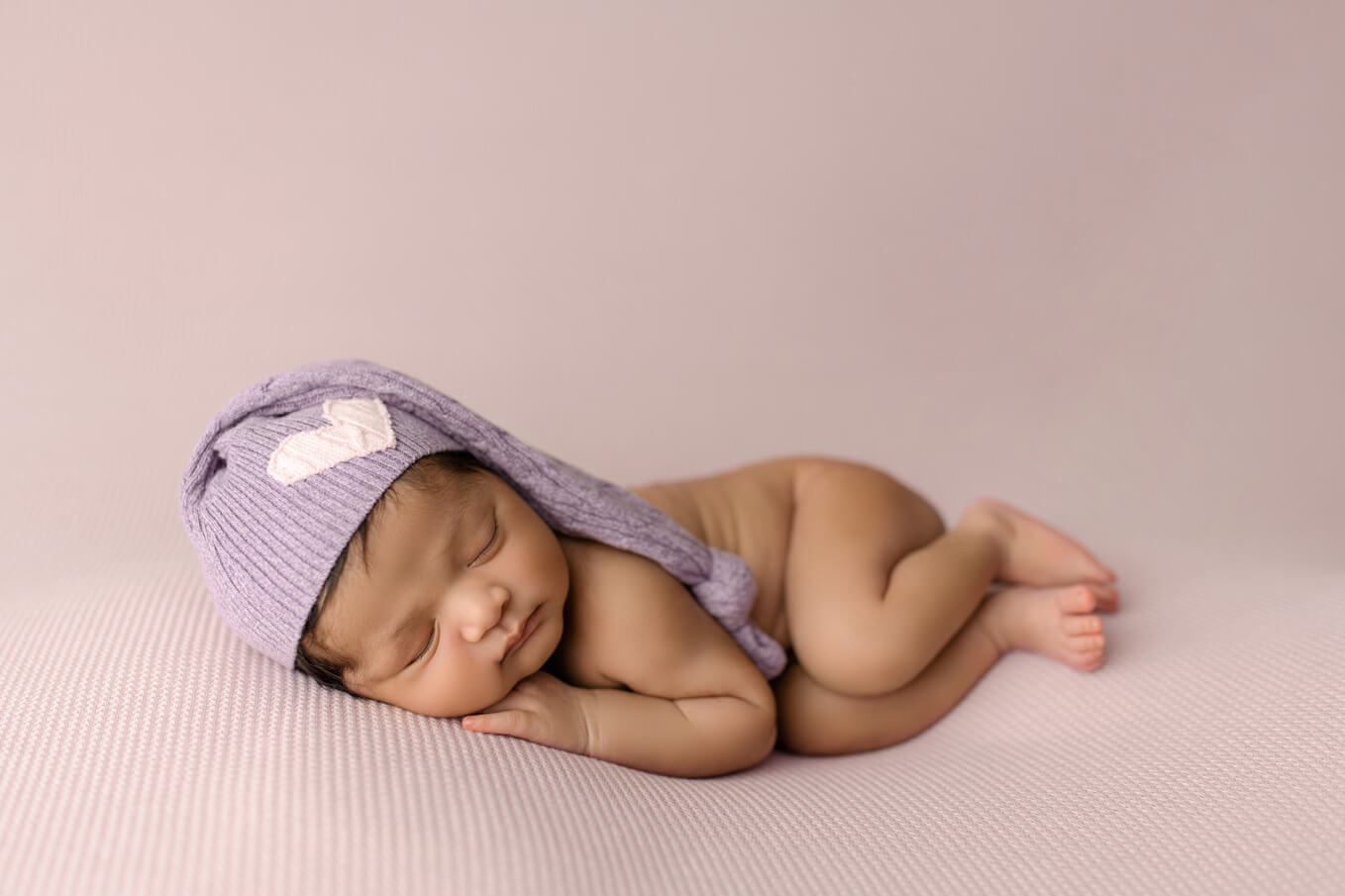 newborn girl in hat on purple