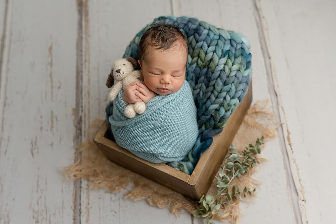 how to choose a newborn photographer style baby in blue wrap on prop