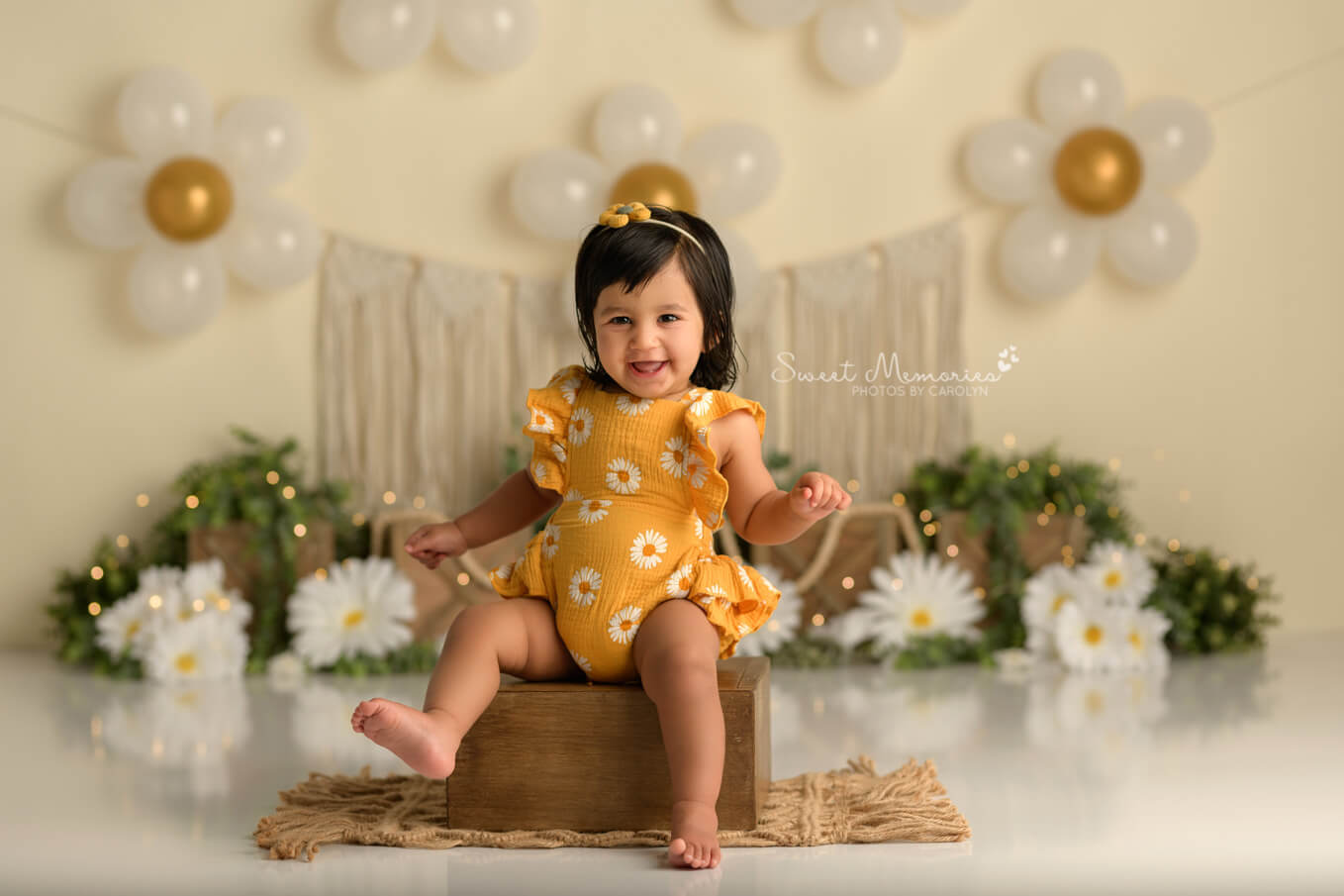 one year old baby girl smiling with boho daisy backdrop | First birthday cake smash photography Round Rock TX
