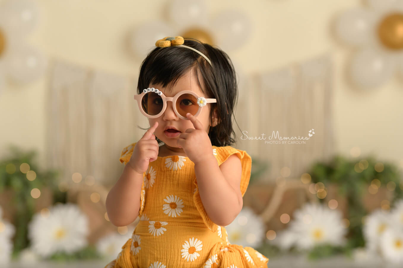 one year old baby girl wearing daisy sunglasses with boho daisy backdrop | First birthday cake smash photography Round Rock TX