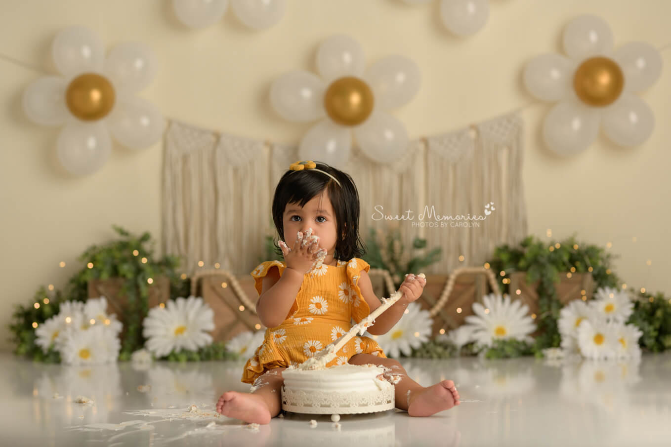 one year old baby girl eating cake with boho daisy backdrop | First birthday cake smash photography Round Rock TX
