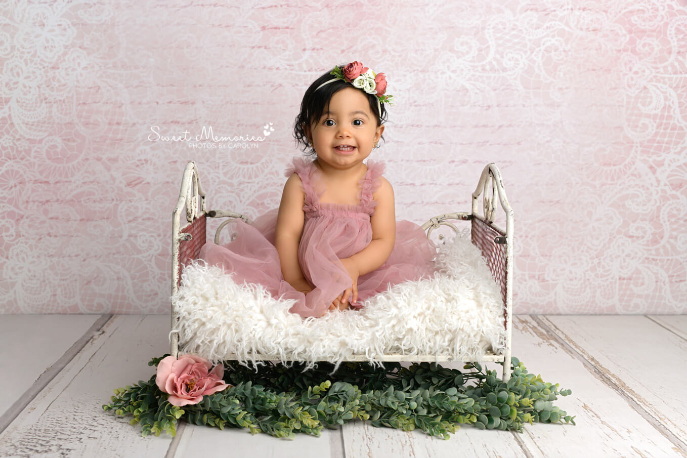 Smiling baby girl sitting on bed prop with pink backdrop | Austin cake smash photography