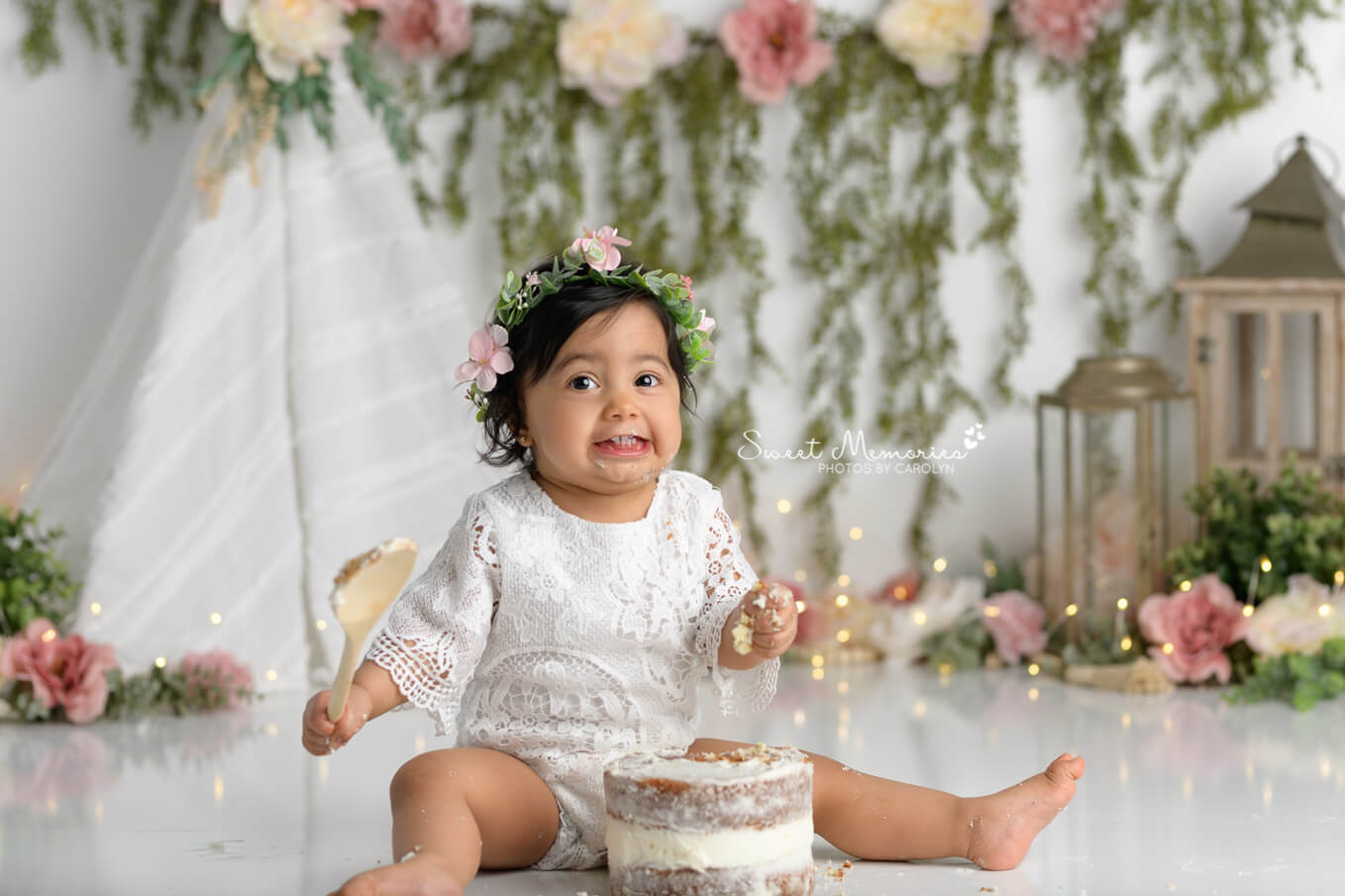 one year old girl making silly face with cake boho floral backdrop | Austin cake smash photography