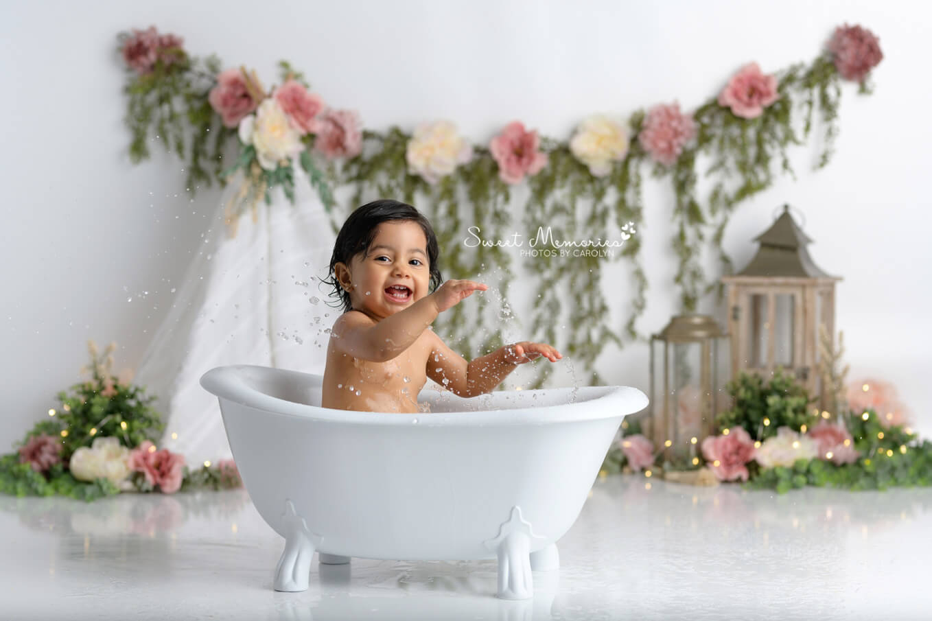 baby girl splashing in tub with boho floral backdrop | Austin cake smash photography