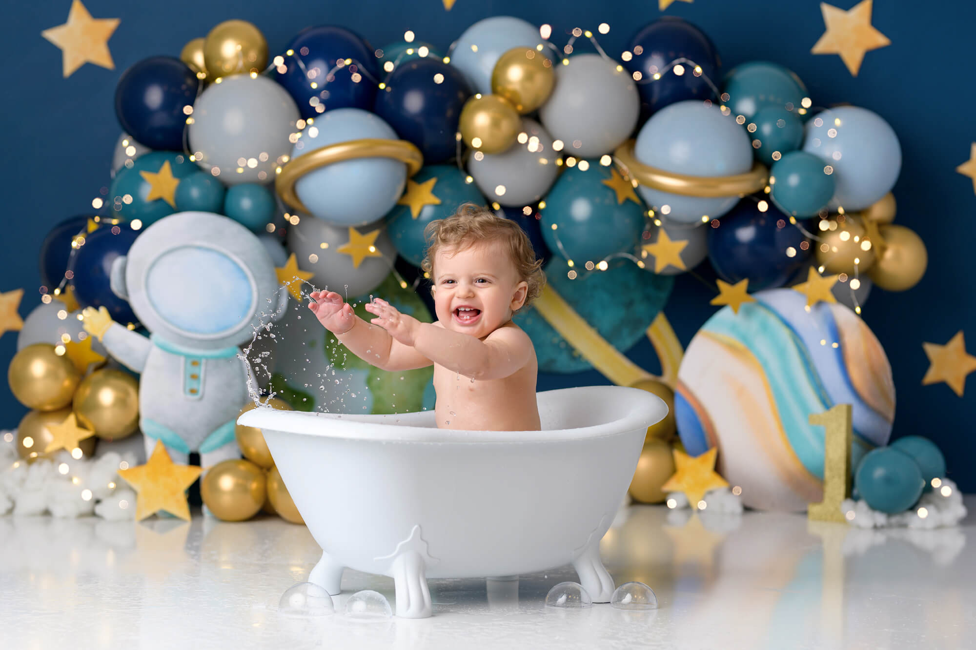 Baby boy splashing in tub at space themed first birthday cake smash with Sweet Memories Photos by Carolyn