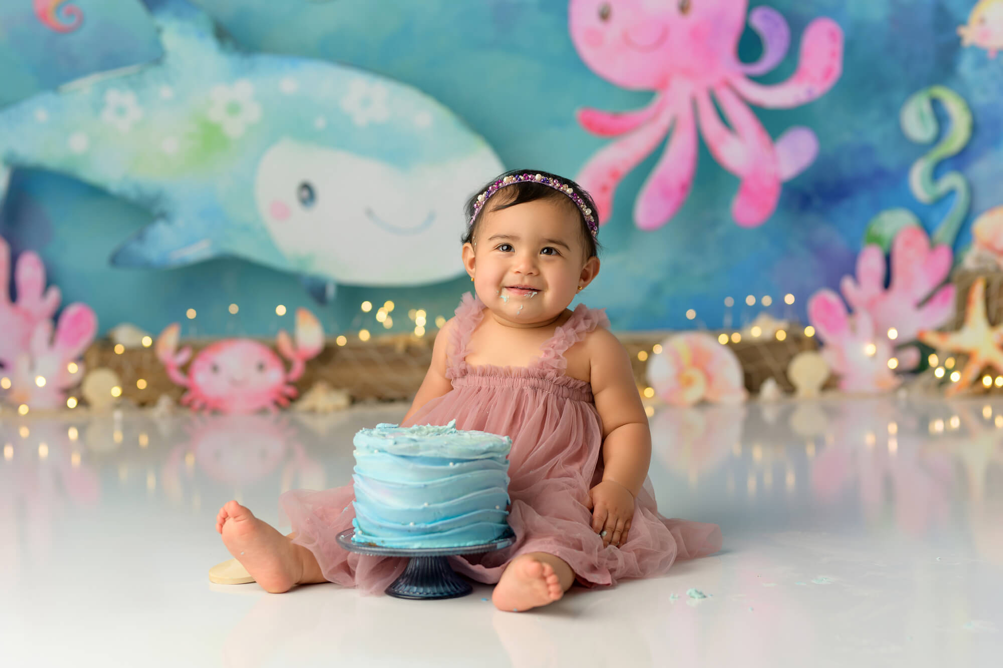 Baby girl sitting with cake at under the sea themed first birthday cake smash with Sweet Memories Photos by Carolyn